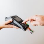 Close-up of card payment using POS terminal, emphasizing cashless transaction.